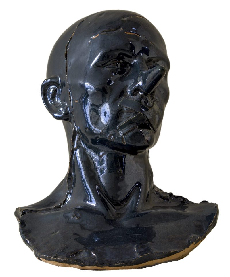 Busto in ceramica nero raffigurante il volto silenzioso di un uomo calvo