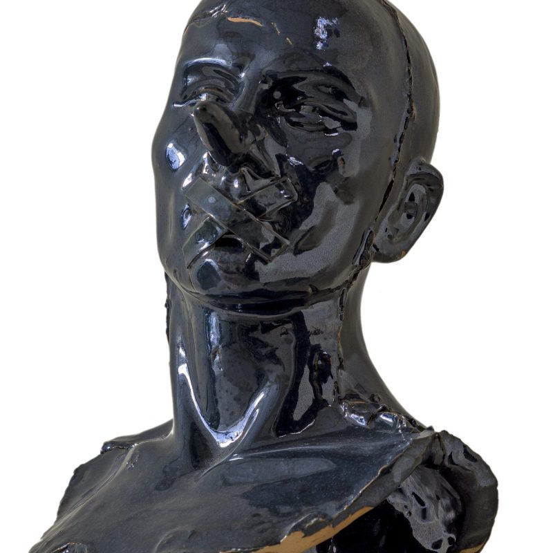 Busto in ceramica nero raffigurante il volto silenzioso di un uomo calvo