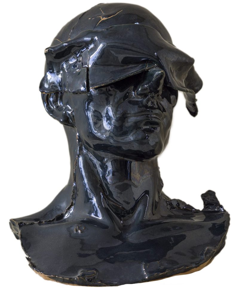 Busto in ceramica nero raffigurante il volto silenzioso di un uomo calvo a cui vengono velati gli occhi