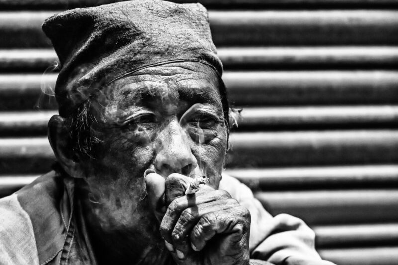 Il fumatore (Nepal): Un vecchio si gode il suo tabacco seduto al sole, in balia dei suoi pensieri.