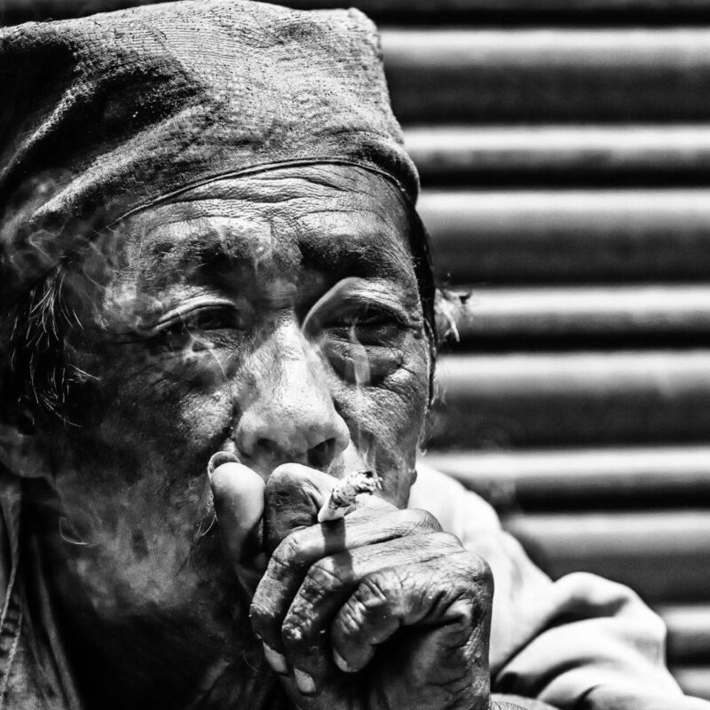 Il fumatore (Nepal): Un vecchio si gode il suo tabacco seduto al sole, in balia dei suoi pensieri.